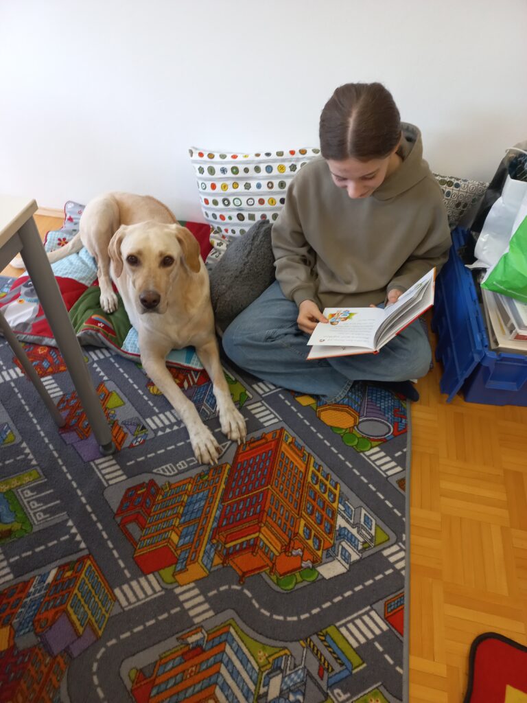 Der Rechtschreibhund Lia hört aufmerksam einem Kind zu.